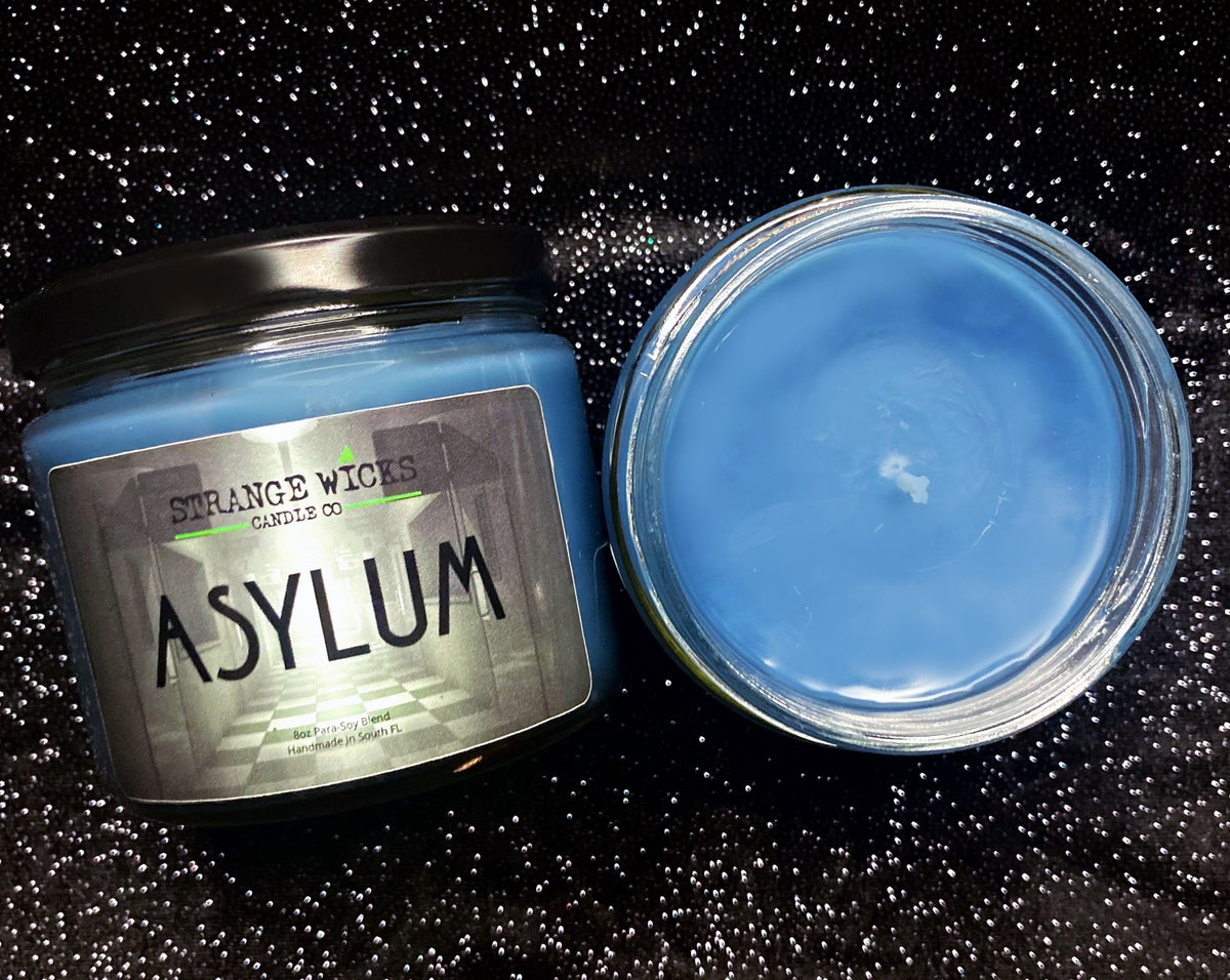 Asylum AHS Candle – blue candle with asylum-hallway label, beside open wax top