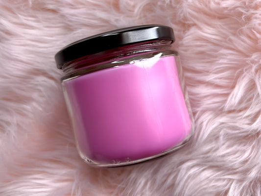 Book Lover candle jar with black lid showing pink wax, label turned away