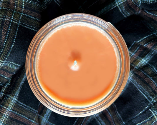 Top-down view of the open Red Jamie candle's smooth orange wax