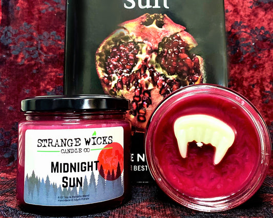 Midnight Sun candle styled in front of a book with a pomegranate cover