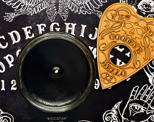 Top-down view of the open Ouija candle's black wax beside a wooden planchette