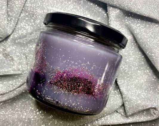 Nesta candle jar with purple glitter wax and black lid on silver fabric