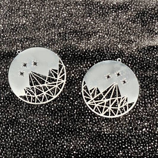 Close-up of Night Court Carousel charms etched with mountain and star designs