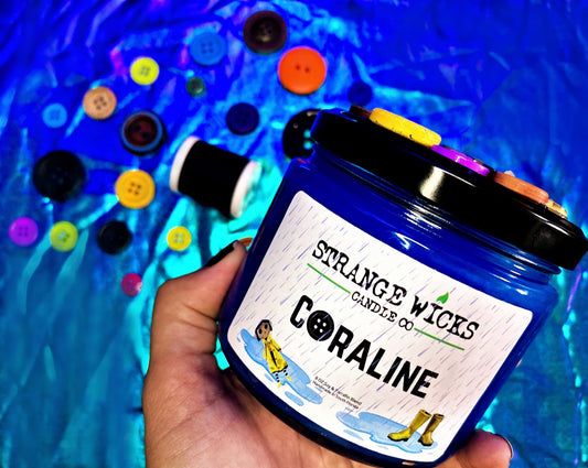 Hand holding Coraline candle with scattered buttons behind