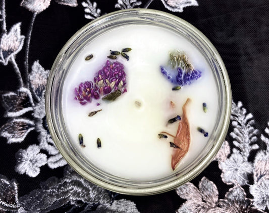 Top-down view of open Folklore candle with white wax and dried flowers on black lace
