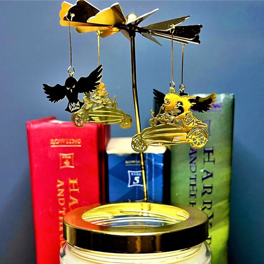 Magical Motorbike Candle Carousel spinning topper resting on jar lid, books behind