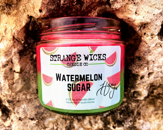 Open Watermelon Sugar candle showing bright pink wax, jar nestled in a rock crevice
